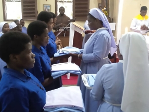 Mhudumu Mkuu wa Shirika la Dada Wadogo, Jimbo Kuu Katoliki la Dar es Salaam, Sista Doreen Mwakaliku, akiwakabidhi nguo baada ya kupandishwa hadhi ya utawa Wapostulanti na kuwa Wanovisi katika Shirika hilo.