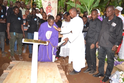 Paroko Msaidizi wa Parokia ya Bikira Maria Mshindaji, Jimbo Katoliki la Kigoma, Padri George Muhanuka, akisimika Msalaba kwenye kaburi la marehemu Theresia Nicholaus Massawe. (Picha na Yohana Kasosi)